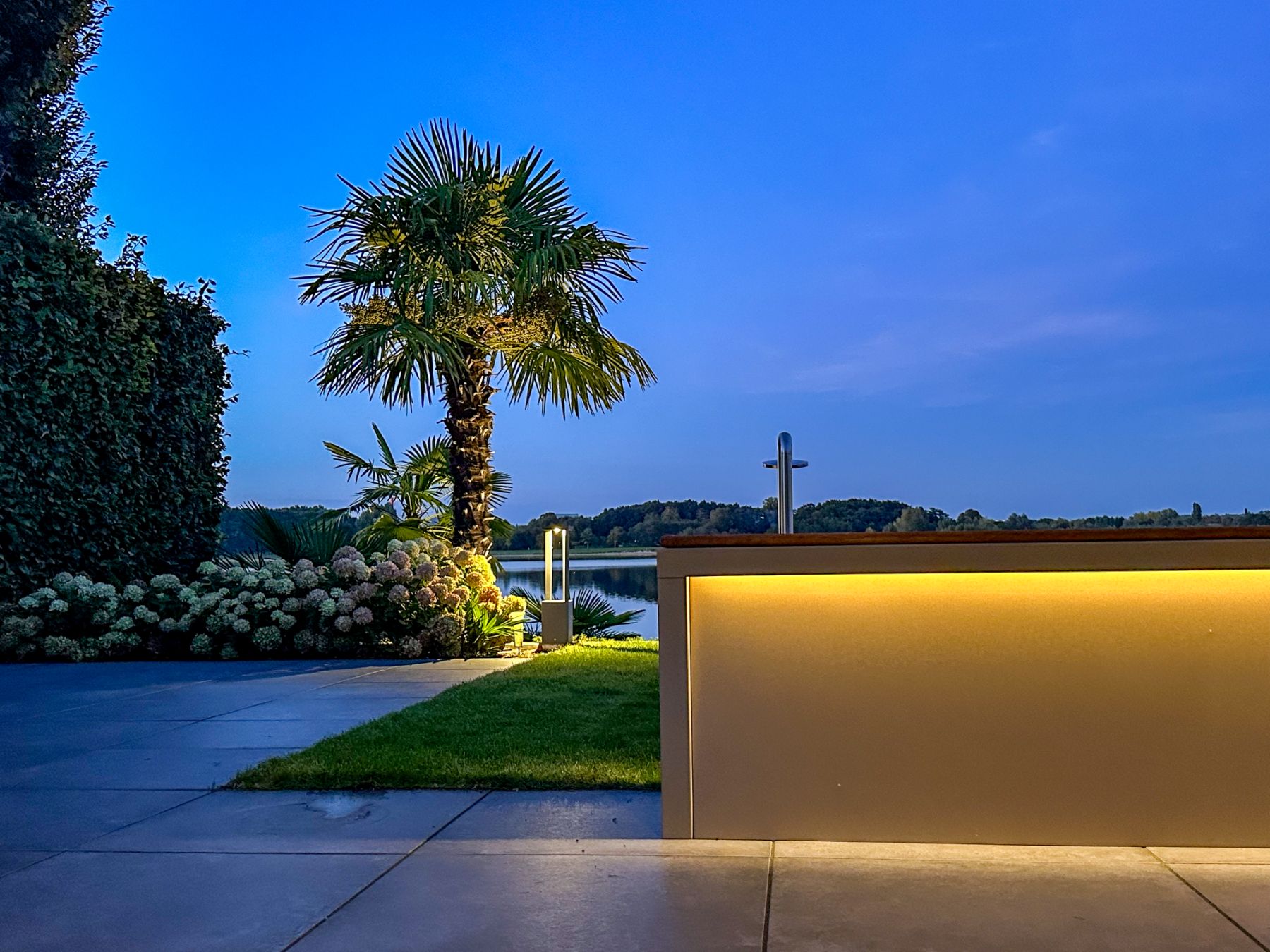 GLOOI plantenbak met zitting en geïntegreerde verlichting in een tuin bij avond